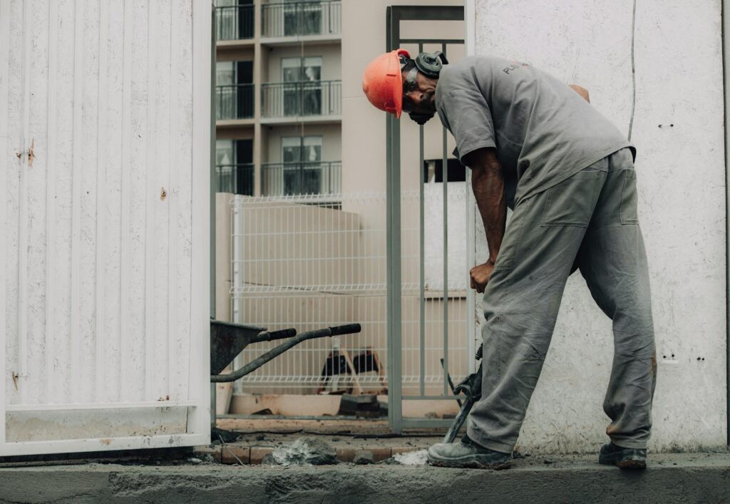 Man in hard hat operating a jackhammer on an outdoor construction site.