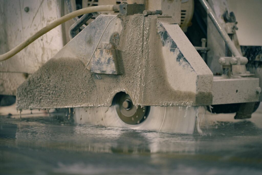 Close-up of a concrete saw cutting a floor, showcasing industrial machinery in action.